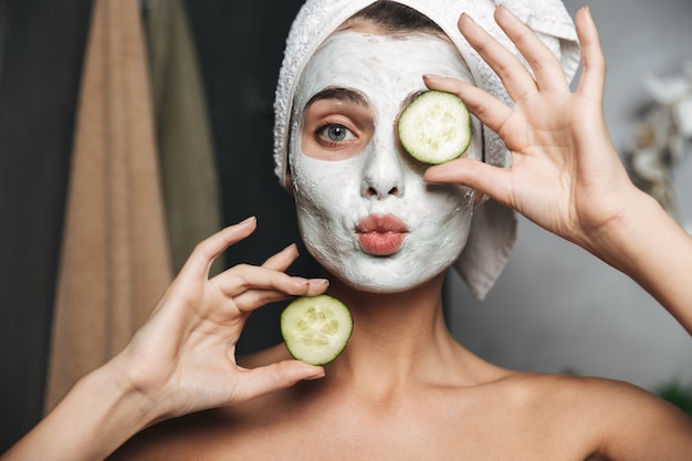 Photo beautiful young woman with towel wrapped around her head wearing face mask