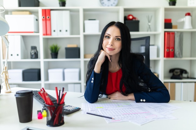 Beautiful young woman working with documents in the office. On the table are papers and a pencil.