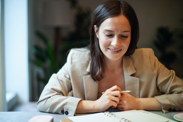 Beautiful young woman writing her business plans on diary