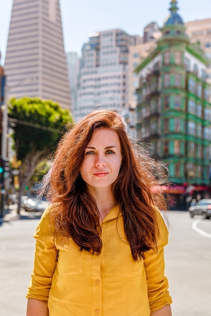 beautiful young woman in a yellow shirt in a business center with a view of the transamerica tower