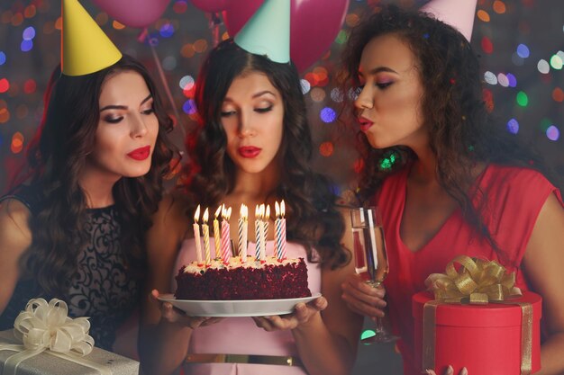 Foto belle giovani donne che spengono le candeline sulla torta di compleanno alla festa