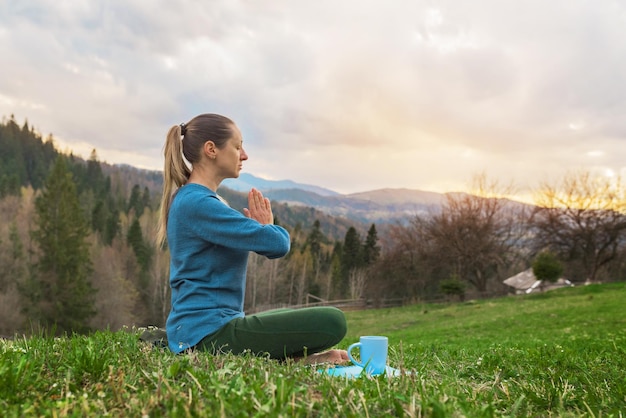 Bella giovane donna meditazione yoga assana rilassante nella natura in montagna