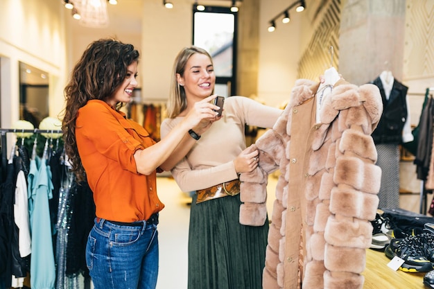 Beautiful young women trying elegant clothes in expensive boutique or store.