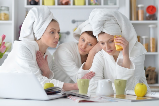 Beautiful young women wearing a white bathrobes with laptop  and  tea at home