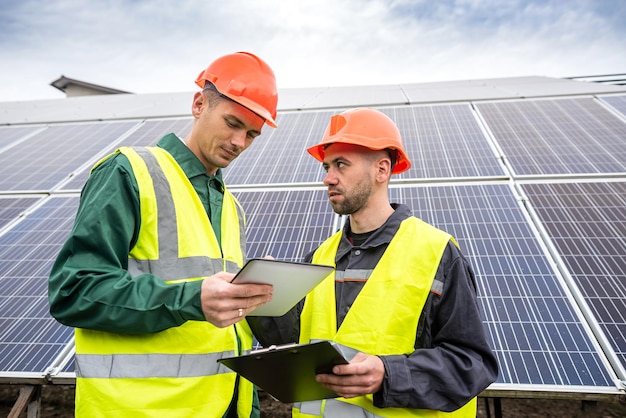 Beautiful young workers in special clothes write down a plan to install solar panels. Green electricity concept