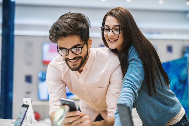 Beautiful youthful boyfriend and girlfriend checking mobile while buying in the mobile shop.