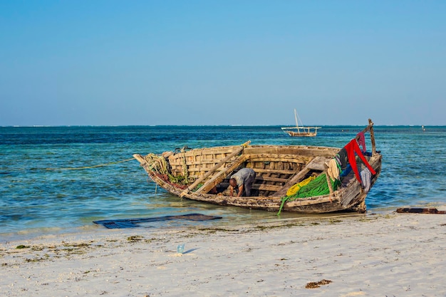 Beautiful Zanzibar coast line. Wooden fisherman boats on sandy beach with blue water background