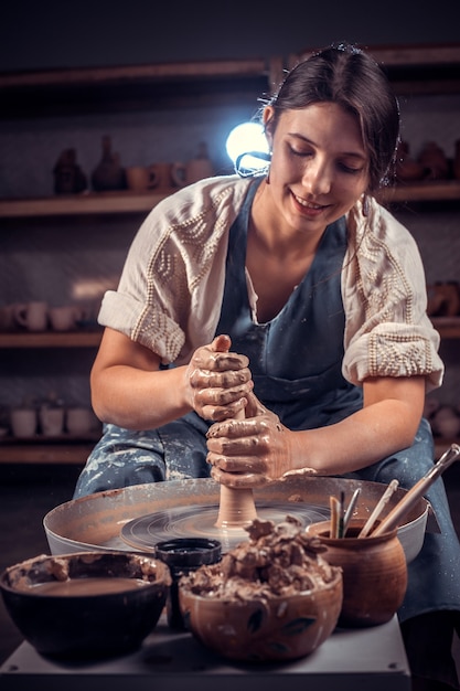 손으로 원시 점토와 포터의 바퀴에서 작업하는 Beautifulceramist 여자