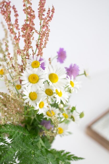 Beautifull daisies and other flowers on a white table.