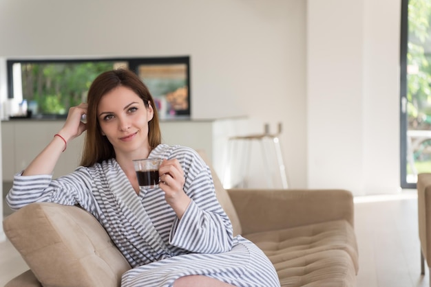 Beautifull young woman in a bathrobe enjoying morning coffee in her luxurious home villa