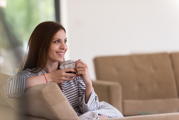 彼女の豪華な家の別荘で朝のコーヒーを楽しんでいるバスローブを着た美しい若い女性