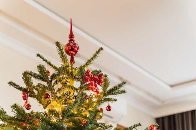 Foto albero di natale all'interno splendidamente decorato con un topper rosso in cima con spazio di copia