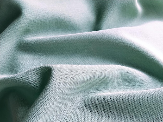 Beautifully folded light green fabric Soft pleasant waves and flounces on textiles Closeup Drapery for curtains fabric for dressmaking or upholstery