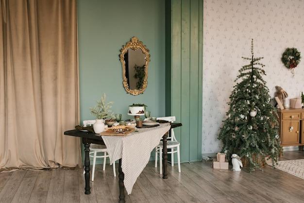 Красиво выложенный стол и рождественская елка в гостиной, украшенные на праздник