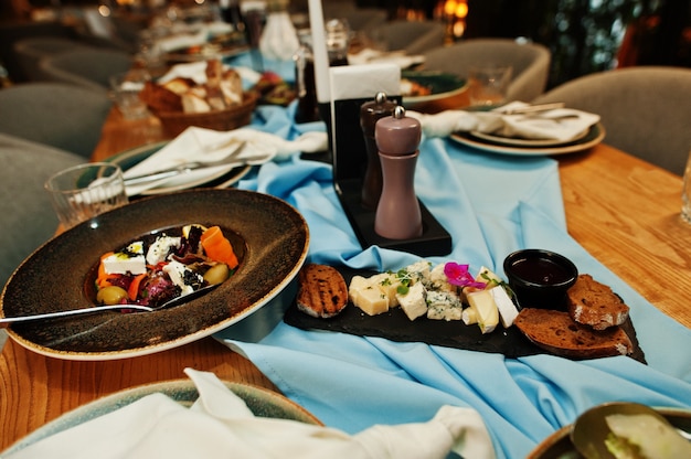 Beautifully laid tables with food, glasses and appliances in restaurant.