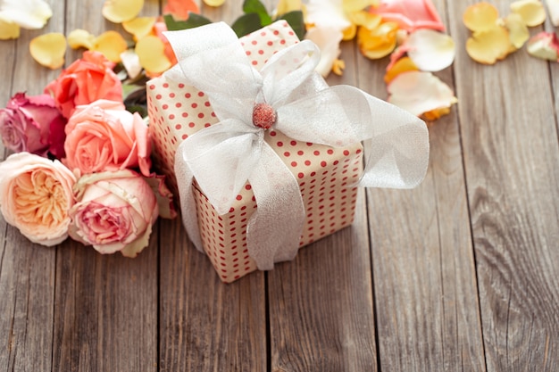 Scatola regalo splendidamente incartata e rose fresche per san valentino o la festa della donna. concetto di vacanza.