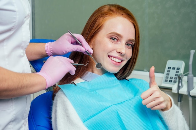 美しい赤毛の生姜の女性が歯科医院に座り、クリニックで歯科医に会いに来ました。