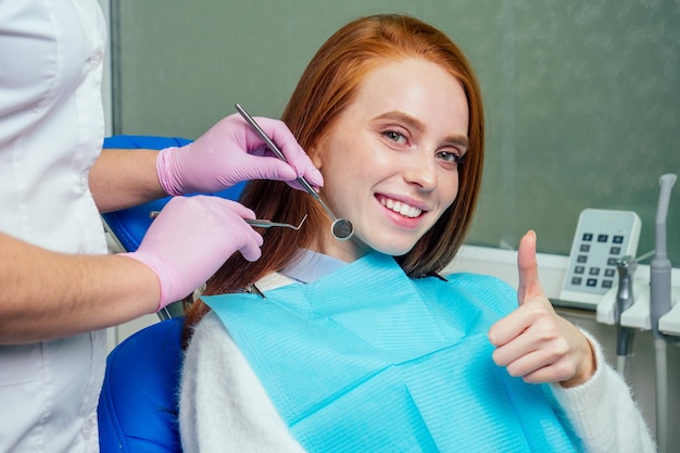 La bella donna dello zenzero dai capelli rossi si siede sulla poltrona del dentista. è venuta a vedere il dentista in clinica.