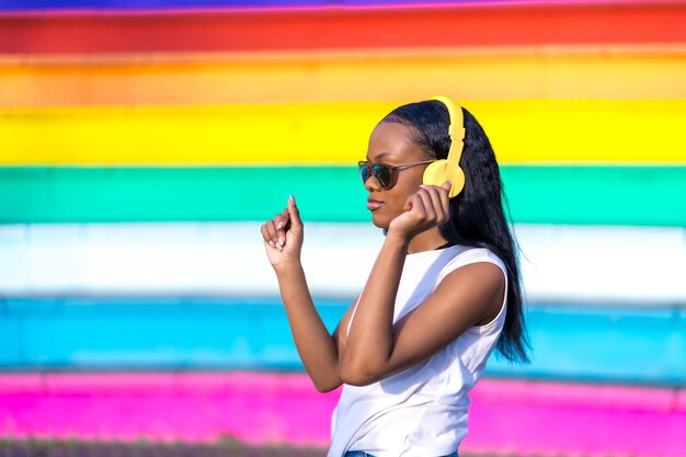 Beauty african woman with headphones dancing in an urban park