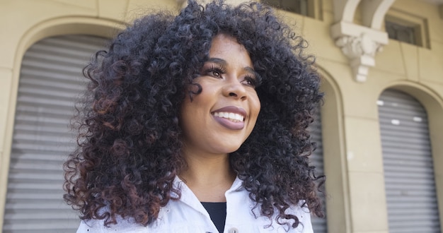 Beauty Afro American woman looking at the horizon. Pretty woman with curly hair feeling peaceful. Cute black female enjoying fresh air thinking about life, optimistic.