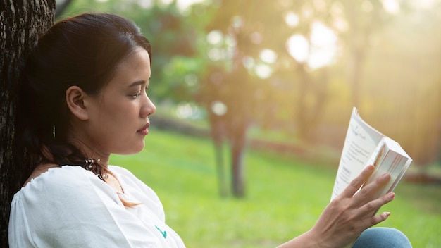 Beauty asian woman reading book at park on sunset.