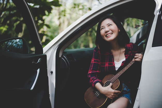 美しさアジアの女性は、笑顔と屋外で楽しむ白い車でウクレレと夏。