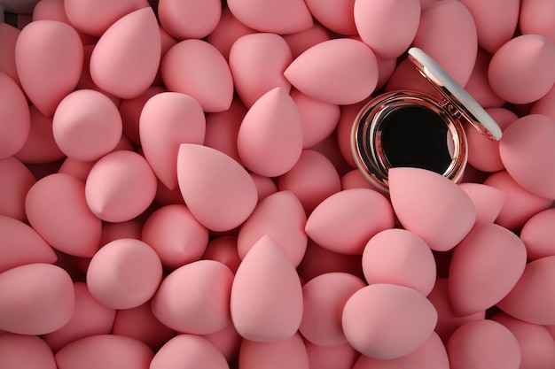 Beauty background a bunch of pink gentle makeup sponges and a mirror