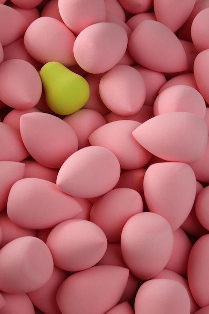 Photo beauty background a bunch of pink gentle sponges and one contrast green conflict for makeup vertical