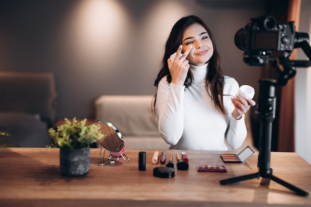 Beauty blogger vrouw filmt dagelijkse make-up routine tutorial op camera. Influencer jonge vrouw live streaming cosmetica product review in thuisstudio. Vlogger baan. Doe-het-zelf.