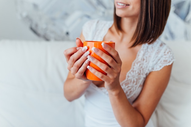 ナイトガウンの美しさの花嫁はコーヒーを飲んでいます。