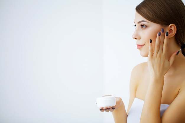 Beauty and Care. Happy Smiling Young Woman Holds Cream for Face. Girl After Shower. Morning Face Care. Pure Skin. High Resolution