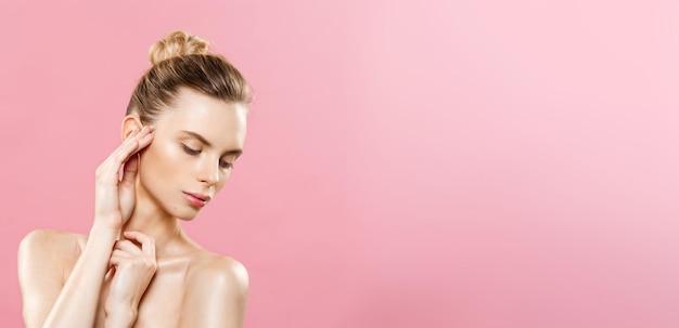 Foto concetto di bellezza bella donna caucasica con trucco naturale della pelle pulita isolata su sfondo rosa brillante con spazio per la copia