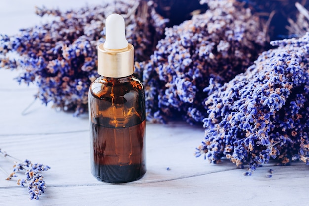Beauty concept. Bottle of lavender oil and lavender sprigs on the wooden background.