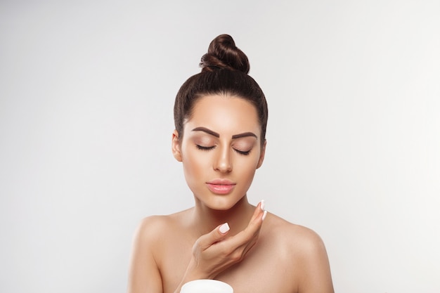 Beauty Concept. Woman Applying  Cosmetics Cream and Smiling