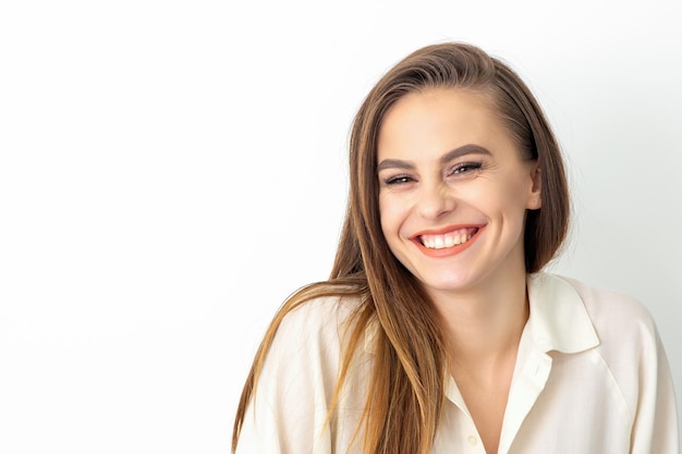 Beauty concept of woman. Portrait of a happy charming shy smiling young caucasian woman with long brown hair posing and looking at the camera over white background.