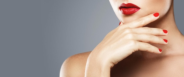 Photo beauty and cosmetics. close-up of female mouth and nails with red manicure and lipstick.