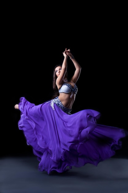 Beauty dancer posing in dark with fly purple veil