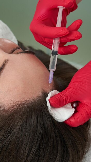 Photo beauty doctor makes hyaluronic acid rejuvenation beauty injections in head of beautiful young female