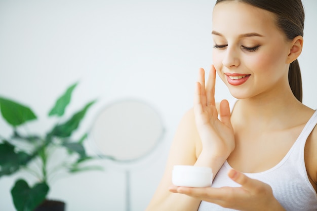 Beauty Face Care. Woman Applying Cream On Skin.