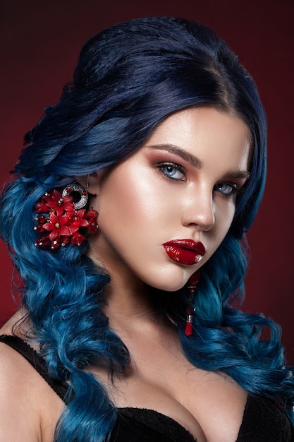 Beauty face of a girl with blue hair with a braid hair. Professional make-up, clean skin, shot against a dark background.