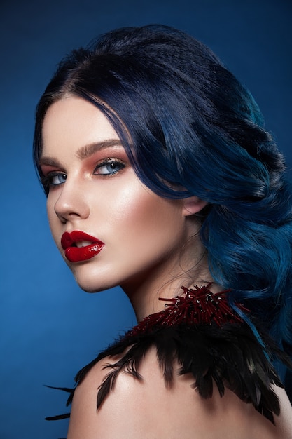 Лицо красоты девушки с голубыми волосами и косой. Профессиональный макияж, чистая кожа, снято на темном фоне.