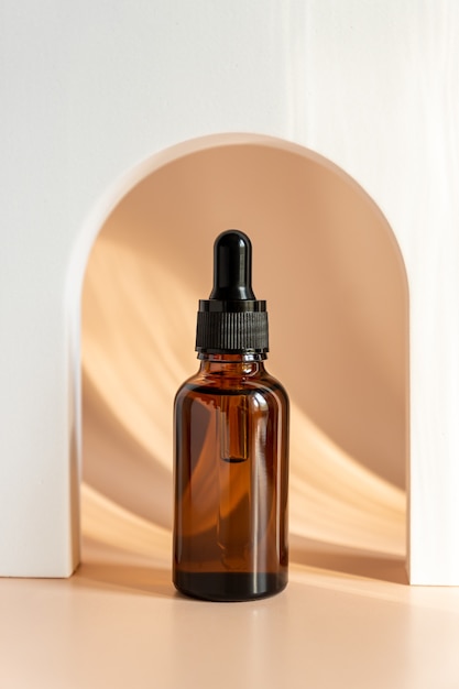 Beauty face oil in amber glass dropper bottle in Arch. Trendy shoot of cosmetics packaging. Essential oil with natural ingredients. Cruelty free cosmetics.