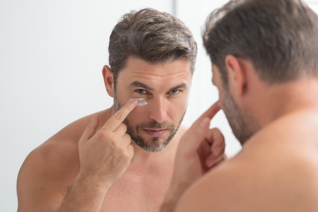 Beauty face portrait of a beautiful man applying face cream skincare cream for man mask skin lifting