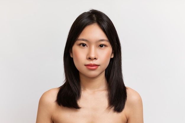 Beauty face portrait of japanese lady with natural makeup and healthy skin looking at camera over