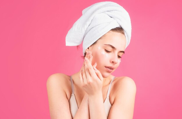 Beauty face portrait spa therapy beautiful woman in towel takes care of skin isolated on pink