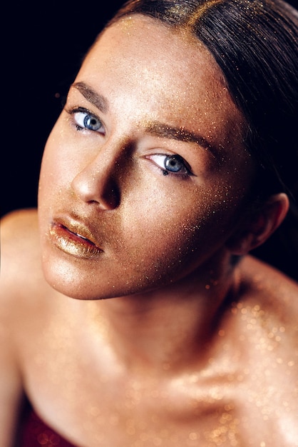 Photo beauty fashion art model girl with golden skin. close up portrait of girl with blue eyes on black background