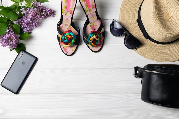 Beauty fashion composition with shoes hat sunglasses cellphone and flowers on white wooden