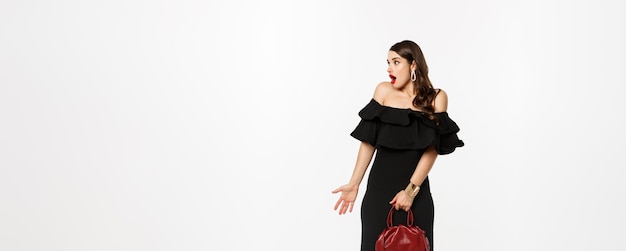 Beauty and fashion concept full length of surprised woman in elegant dress heels looking left confus