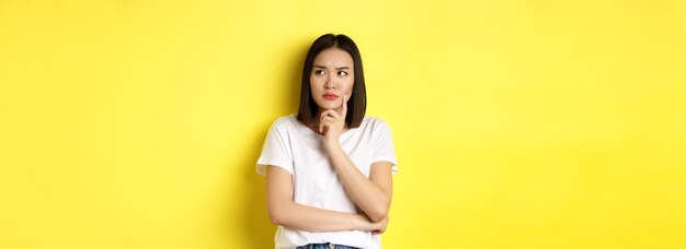 Photo beauty and fashion concept pensive asian woman thinking looking thoughtful while pondering something