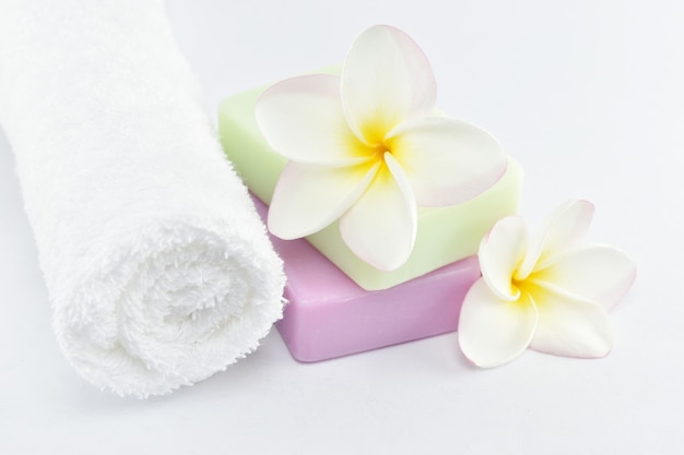 Beauty and fashion concept white towels natural soap and plumeria on white background